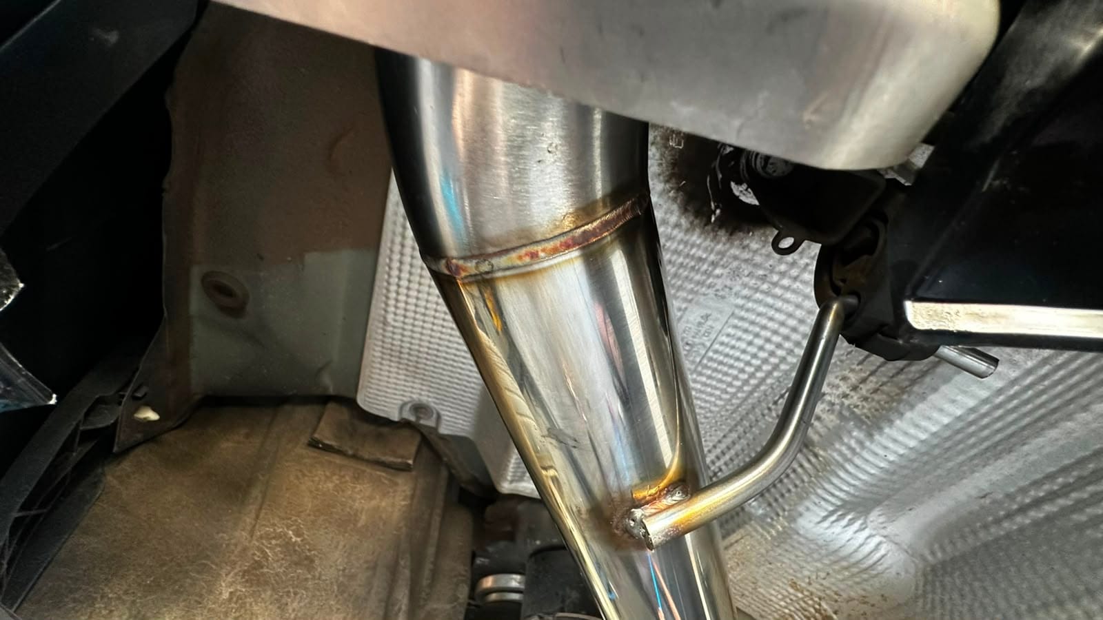 Junta soldada em tubo de escapamento de inox polido, com têmpera de calor dourada na costura